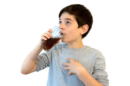 Cute boy drinking soft drink.Caucasian kid drinking coke from a glass. Isolated on white.の写真素材