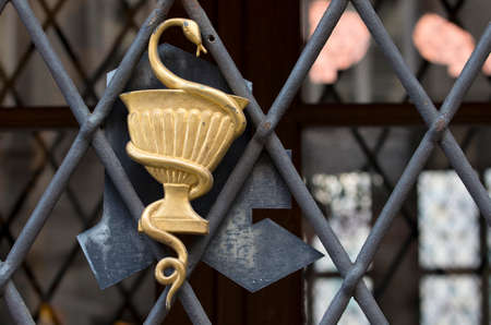 Old german pharmacy sign.Cast iron pot with snake on one of Residence palase doors. Munich,...