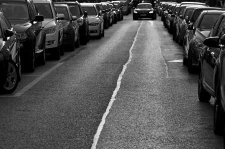 Cars parked on the roadside.Black and white urban image of a row of parked cars. Busy street with lots of traffic.の写真素材