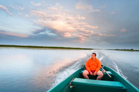 man in boat on Volga in sunsetの写真素材