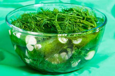 Glass bowl with marinate cucumbers on greenの写真素材