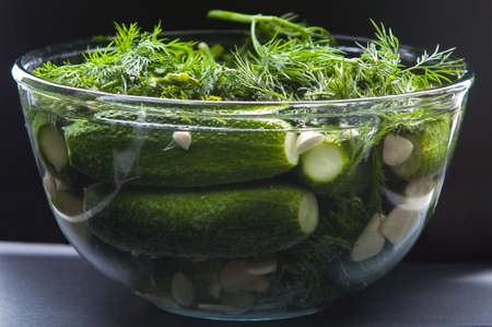 Glass bowl with marinate cucumbers on blackの写真素材
