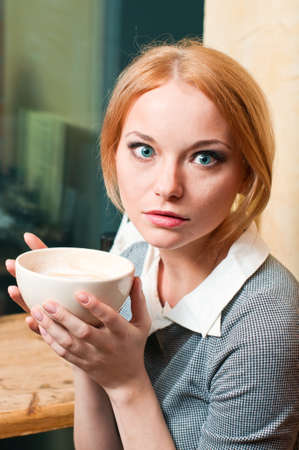 emotional woman with cup of coffee in grey suitの写真素材