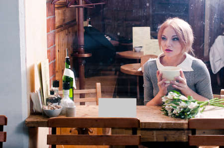 woman with cup of coffee in grey suit behind cafe window