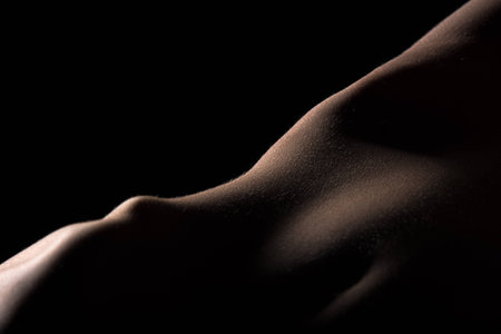 Skin on womans thigh hardly lighted like reliefの写真素材