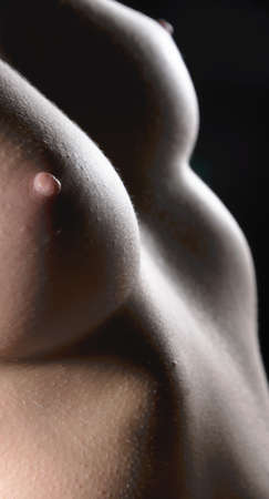 Female body with open breast on dark backgroundの写真素材