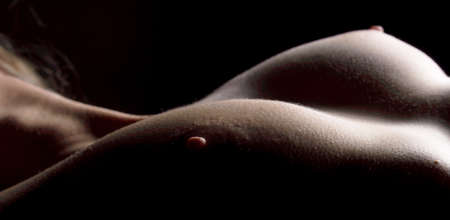 Female body with open breast on dark backgroundの写真素材