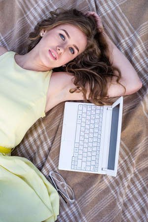 Young freelancer, pretty girl is working with laptop at city park with pondの写真素材