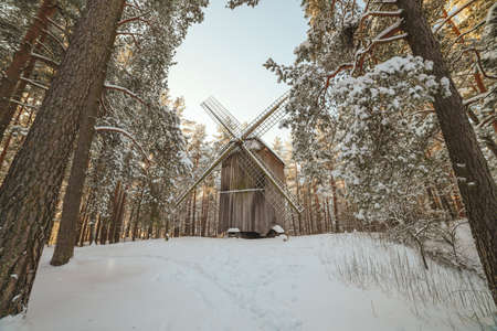 Old wooden windmill in forest in winterの写真素材