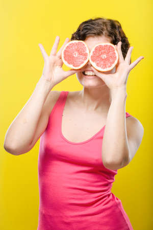 Girl with sliced red grapefruit on colored background. Natural unretouched image.の写真素材