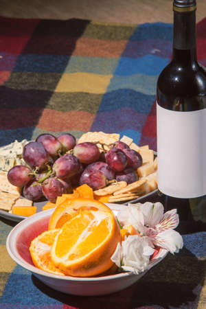 Served table with wine bottle, orange and grape covered with colored blanketの写真素材