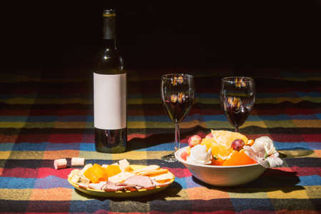 Served table with wine bottle, orange and grape covered with colored blanketの写真素材