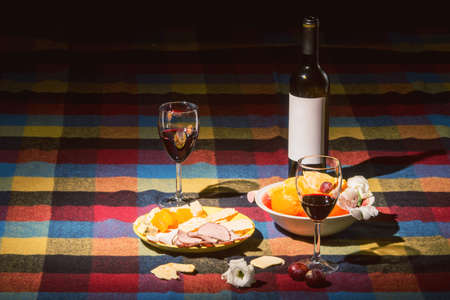 Served table with wine bottle, orange and grape covered with colored blanketの写真素材