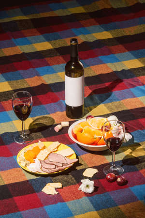 Served table with wine bottle, orange and grape covered with colored blanketの写真素材