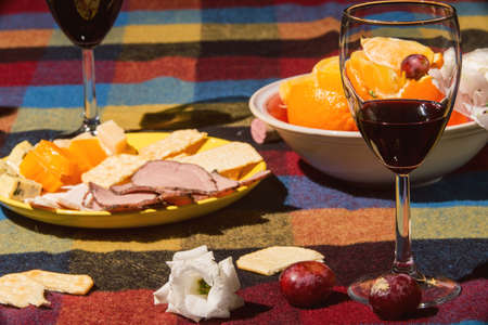 Served table with wine glasses, orange and grape covered with colored blanketの写真素材