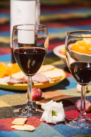 Served table with wine bottle, orange and grape covered with colored blanketの写真素材