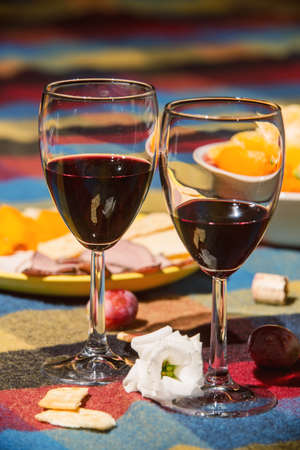 Served table with wine glasses, orange and grape covered with colored blanketの写真素材