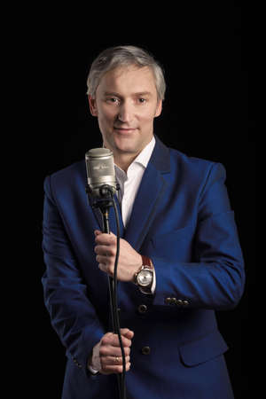 Singer in blue suit standing with microphoneの写真素材