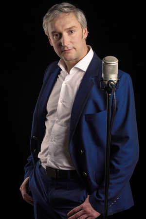 Singer in blue suit standing with microphoneの写真素材