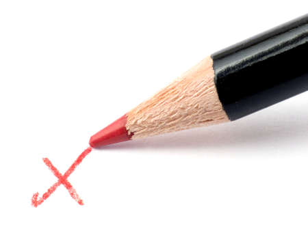 Pencil writing a red cross on a white sheet of paper with shadowの写真素材