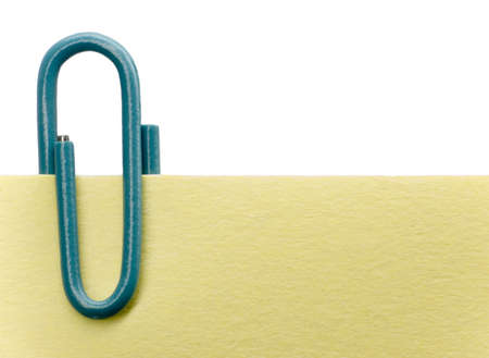 Blue paperclip on a yellow note with white backgroundの写真素材