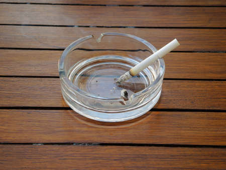 A cigarette smolders in an ashtrayの写真素材