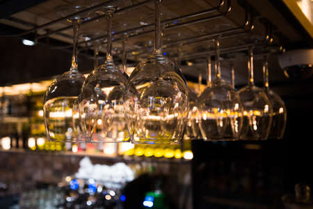 Glasses hang in the restaurant. Warm soft tones and reflections on the glass.