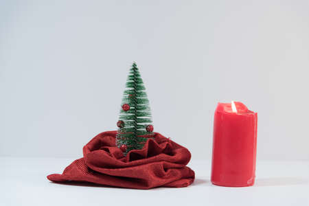 A Christmas tree peeking out of a bag. Toy Christmas tree. Christmas tree in a bag. Christmas composition. red candle in the background.の写真素材