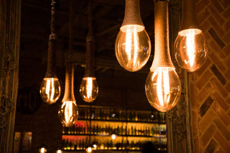 Decorative antique Edison style light bulbs on the background of a mirror that reflects the light bulbs. Soft, subdued light in the restaurant creates a cozy atmosphereの写真素材