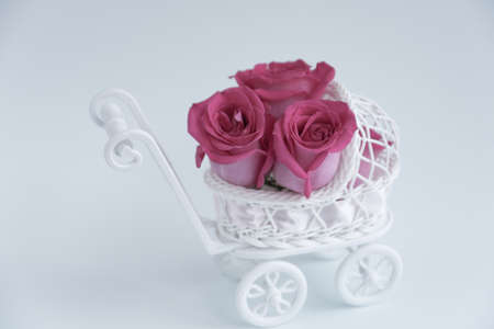 A delicate decorative stroller for newborns filled with pink roses. Concept. Girl, newborn, tenderness. Postcard.の写真素材