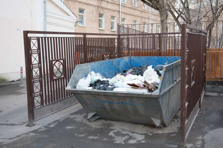 A large garbage can standing in the courtyards of residential buildings. Garbage is placed in a...