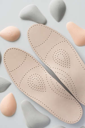 A pair of leather orthopedic insoles surrounded by components. Pelots for unloading the cross arch...