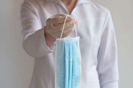 A gloved doctor holds out a medical protective mask. The concept of protectionの写真素材