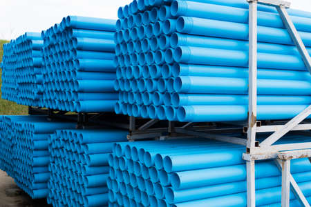 Blue plastic pipes laid on special metal shelving. Production and marketing pipes