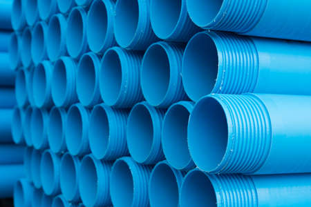 Blue plastic pipes laid on special metal shelving. Production and marketing pipes