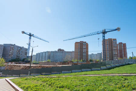 Construction site surrounded by multi-storey buildings. There are cranes on the site. The bright sun shines. skyの写真素材