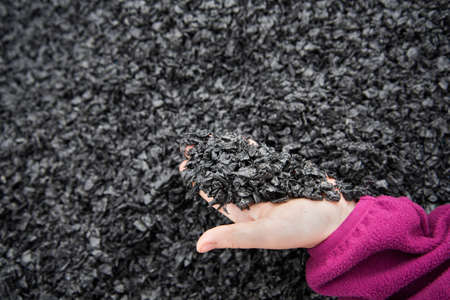 close-up: crushed black plastic for recycling. A child's hand holds crushed particles. The concept of caring for the environment.の写真素材