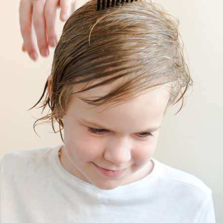 Mom cuts the baby on her own. Home quarantine period. Baby blond is smiling cheerfully. Fun and enjoyable experience.の写真素材