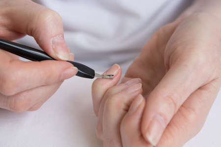 Home manicure. Self-treatment of nails during the pandemic and quarantine. Cuticle removal with a special tool.の写真素材