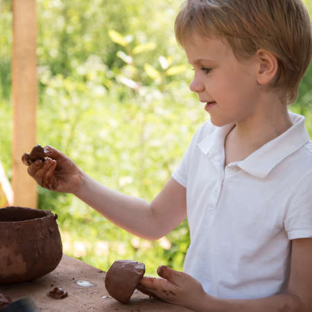 The child makes dishes and various figures from clay. Pottery skills. Hobbies and interests. Childrens education, expanding horizons.の写真素材