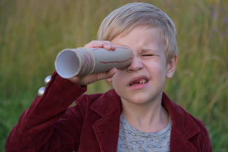 the child looks into a homemade telescopeの写真素材