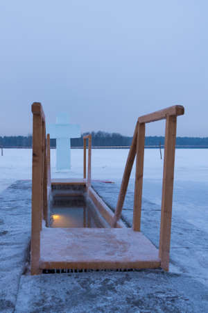 A hole for bathing on the feast of Epiphany. Outdoor plunge pool, the lake. A cross made of iceの写真素材