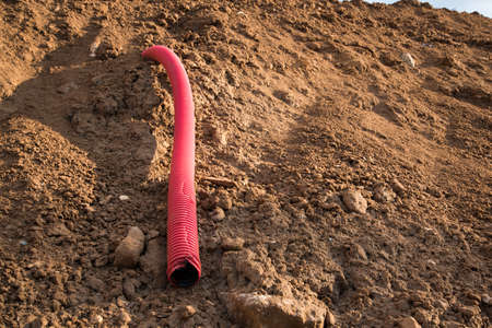 Sewer pipe removed from the ground during the construction phase. Cable channel, taken out from under the building under construction. Construction site. Red corrugated pipeの写真素材