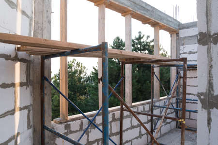 Inside view. House under construction, box of a house without a roof. View from the window. Wall...