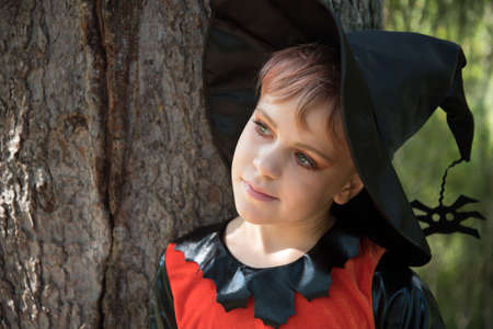 Portrait of a girl dressed as a witch. Beautiful little girl with green eyes. Close-up. The child is...