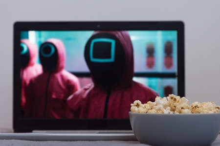Fryazino, Moscow region, Russia - October 24, 2021: Netflix series on laptop screen. The series Squid game . Popcorn is in the foreground. Everything is prepared for watching your favorite TV showのeditorial素材