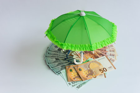 There are 3 different currencies under the open umbrella. Russian ruble, euro, dollar. Tricycle basket. Storing savings in different currencies to reduce risks. Financial protection. Conceptの写真素材