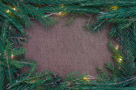 Christmas background. Burlap, branches of a Christmas tree and garlands. Calm, restrained tones. Stylish postcard, invitation, background, place for textの写真素材