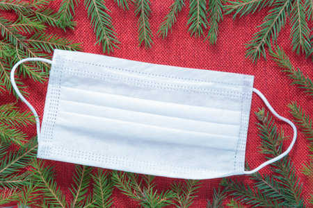 A medical mask lies on a Christmas background. Christmas and virus concept. Holidays protection. There is space for textの写真素材