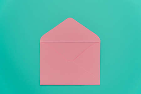 Pink envelope on a bright turquoise background. A clean open envelope with space for text. The basis for the design of a valentine or invitation. Invitation to a wedding, birthday, engagement and more. Non-standard and stylish colors. High quality photoの写真素材